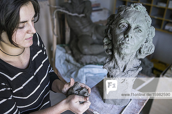 Female student forming clay for bust