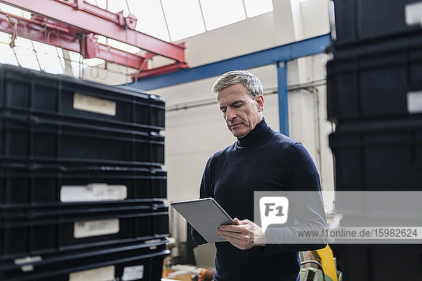 Male supervisor using digital tablet in factory