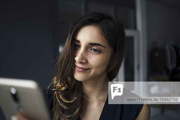 Porträt einer lächelnden jungen Frau  die auf ihr Mobiltelefon schaut
