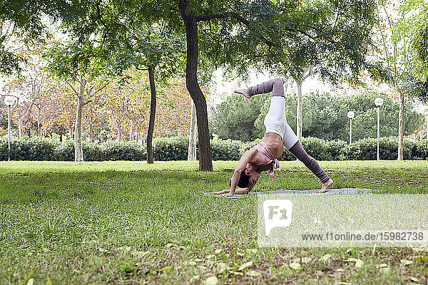 Mittlere erwachsene Frau übt Yoga auf einer Matte im Park