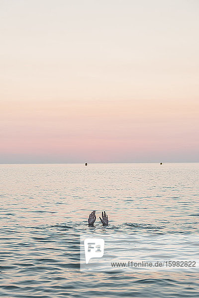 Hände von Teenager-Mädchen im Meer bei Sonnenaufgang