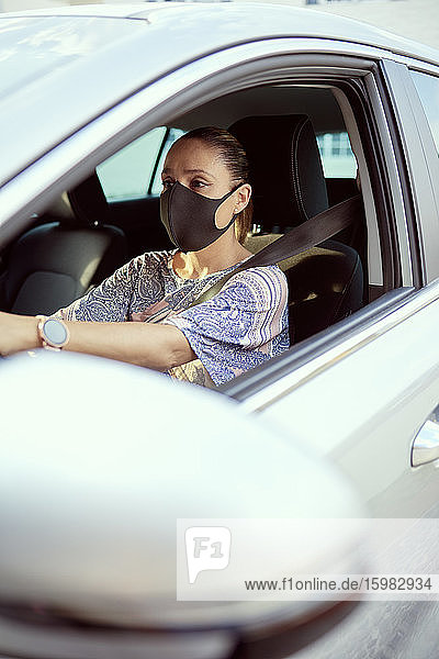 Frau mit Gesichtsmaske beim Autofahren