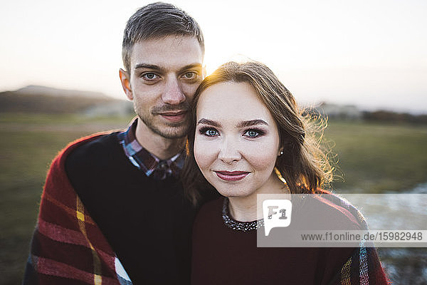 Ukraine  Crimea  Young couple covered with plaid at sunset