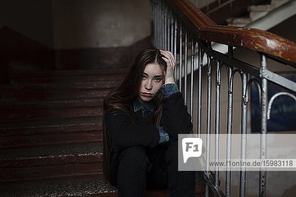 Porträt einer jungen Frau  die auf einer Treppe sitzt