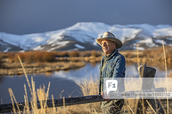 USA  Idaho  Sun Valley  Älterer Mann lehnt am Zaun und schaut auf die Aussicht