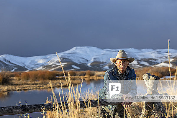 USA  Idaho  Sun Valley  älterer Mann mit Cowboyhut  der sich gegen den Zaun lehnt