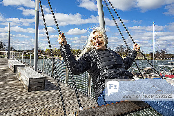 USA  Washington D.C.  Senior woman on swing at Wharf District along Potomac River