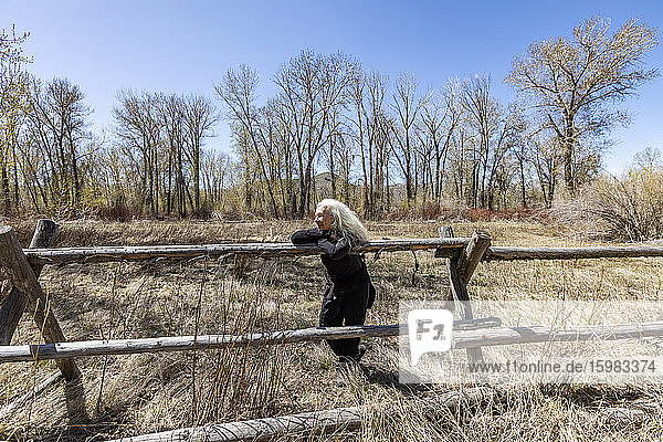 USA  Idaho  Bellevue  Seniorin entspannt sich am rustikalen Zaun