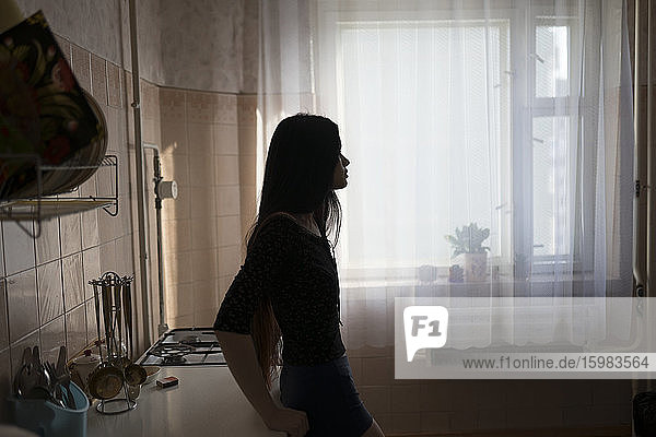 Silhouette einer in der Küche stehenden jungen Frau