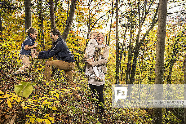 Eltern genießen mit ihren Kindern den Herbst im Wald