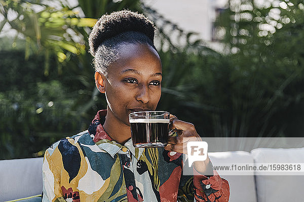 Porträt einer jungen Frau  die im Garten schwarzen Kaffee trinkt