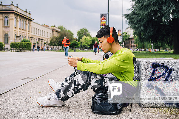 Junger Mann mit Kopfhörern und digitalem Tablet auf dem Fußweg
