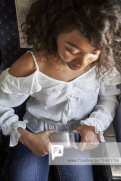 Hohe Winkel Ansicht der jungen weiblichen Passagier Befestigung Sicherheitsgurt beim Sitzen im Flugzeug