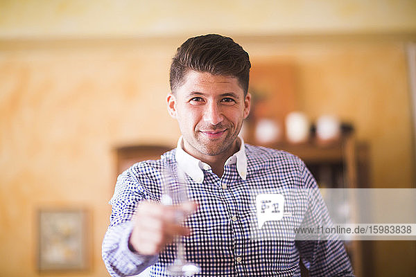 Germany  Lower Saxony  Hannover  Portrait of handsome man holding wine glass toward camera