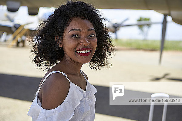 Seitenansicht Porträt der lächelnden jungen Frau auf dem Flughafen Landebahn stehen