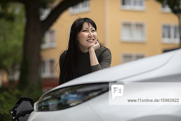 Carsharing  smiling woman charging an electric car