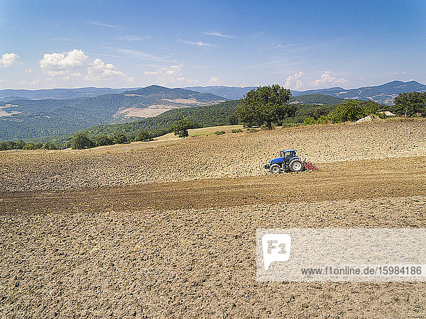 Tractor plowing in farm against sky  Italy