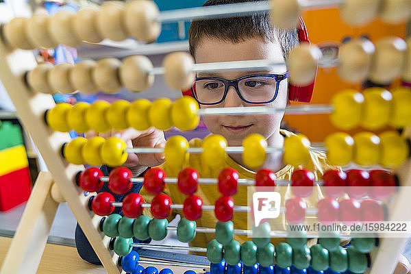 Boy calculating with colorful abacus at home