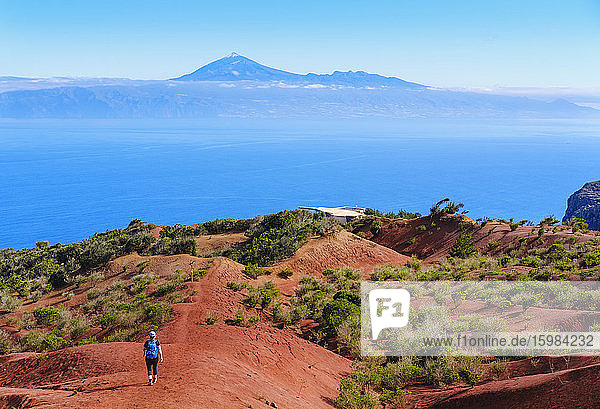 Spain  Canary Islands  Agulo  Female backpacker hiking toward Mirador de Abrante observation point with Mount Teide in distant background