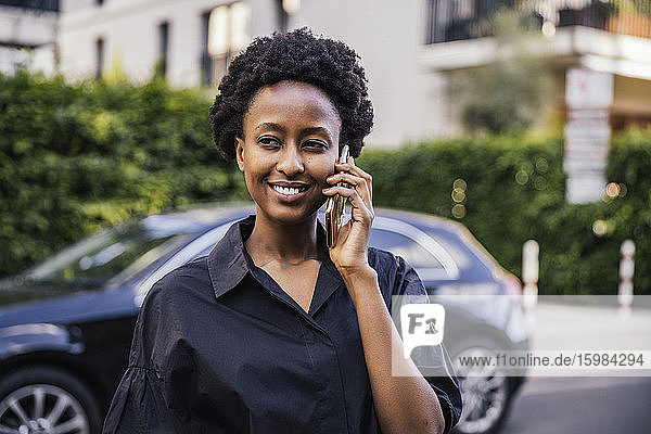 Portrait of smiling young woman on the phone outdoors