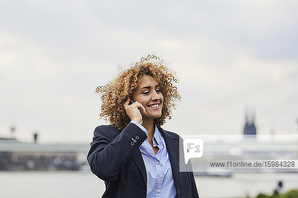 Businesswoman using smartphone at riverside in Cologne  Germany