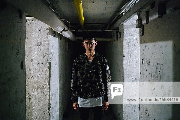 Ernster junger Mann steht in einem Korridor inmitten alter Mauern