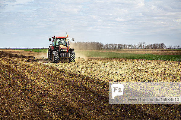 Landwirt im Traktor pflügt Feld im Frühling