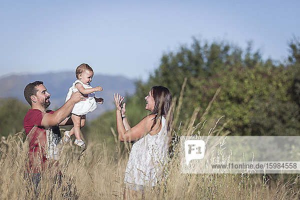 Happy family amidst plants in forest against sky on sunny day