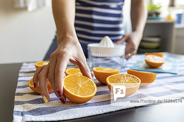 Womanpreparing fresh orange juice  taking sliced orange