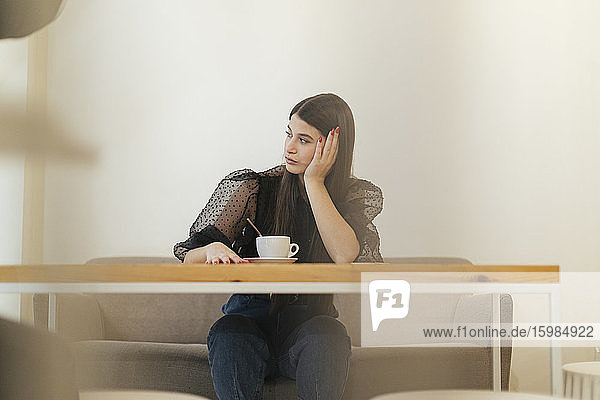 Nachdenkliche junge Frau  die in einem Café sitzt und wegschaut