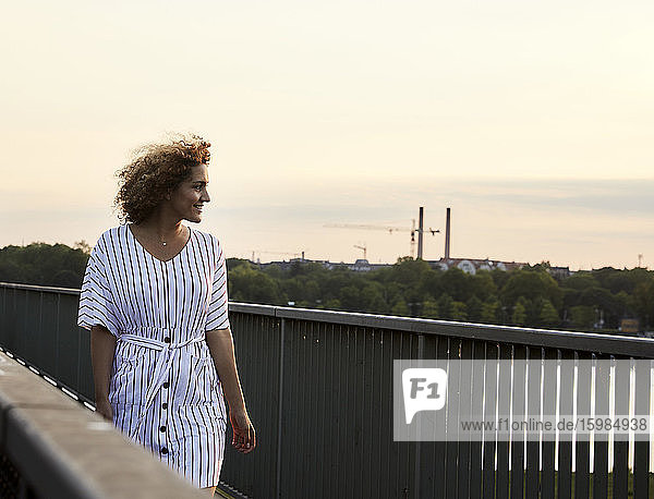 Portrait of smiling woman walking on bridge in the evening