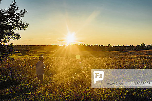Rückansicht eines auf einem Feld spielenden Jungen gegen den Himmel bei Sonnenuntergang  Polen