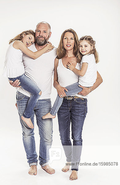 Porträt einer Familie mit zwei Töchtern vor weißem Hintergrund