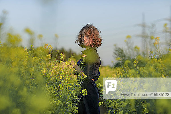 Portrait of teenage girl standing in rape field