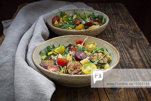 Two bowls of pasta salad with grilled zucchini  tomatoes  arugula  Spanish onion and balsamic vinegar