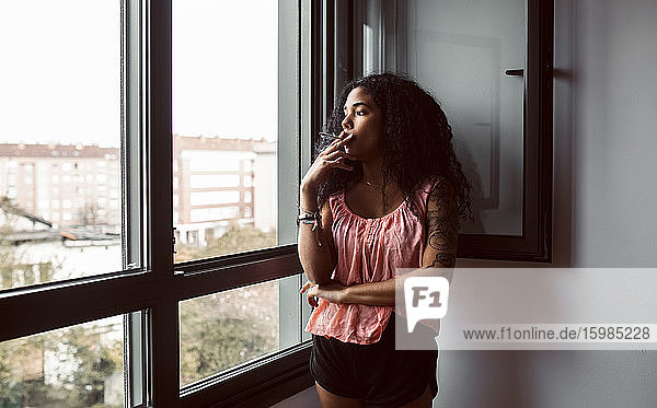 Young woman smoking a cigarette at the window