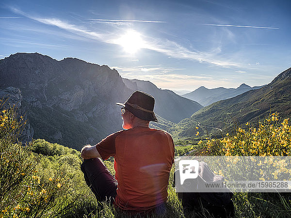 Rear view of senior man sitting on mountain against sky  Alto de La Farrapona  Asturias  Spain
