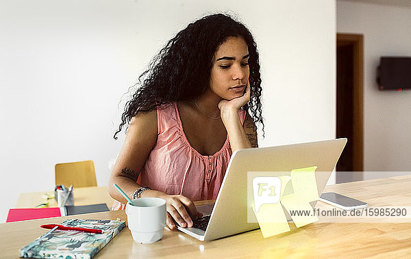 Young woman working from home using laptop