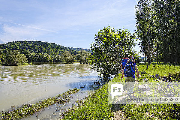 Rear view of man and woman walking by River Isar during sunny day  Bavaria  Germany