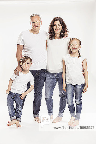 Porträt einer glücklichen Familie mit zwei Kindern  die vor einem weißen Hintergrund stehen