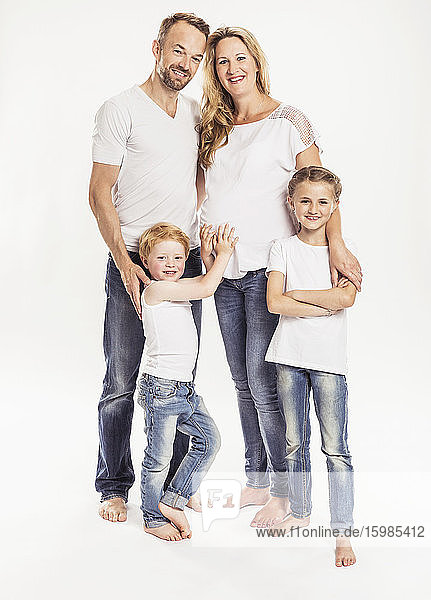 Familienporträt mit schwangerer Mutter und zwei Kindern  die vor einem weißen Hintergrund stehen