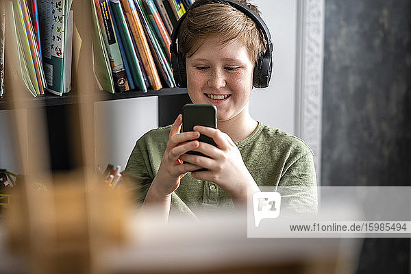 Boy sitting at easel and using smartphone