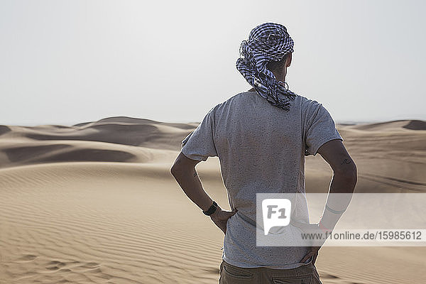 Männlicher Tourist steht auf Sanddünen in der Wüste von Dubai  Vereinigte Arabische Emirate