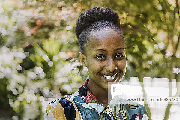Porträt einer glücklichen jungen Frau im Garten