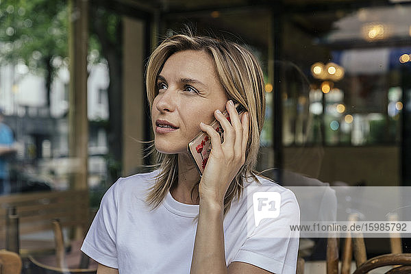 Porträt einer telefonierenden Frau vor einem Kaffeehaus