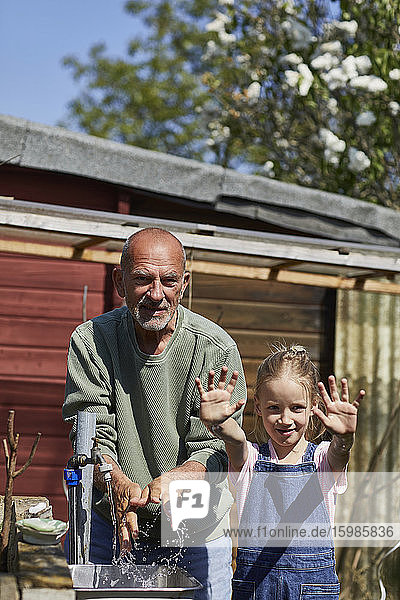 Portrait of girl with grandfather in allotment garden showing her clean hands after washing