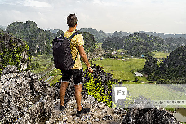 Vietnam  Ninh Binh Province  Ninh Binh  Male hiker admiring scenic landscape of Hong River Delta from top of karst formation