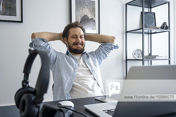 Man using laptop and leaning back at home