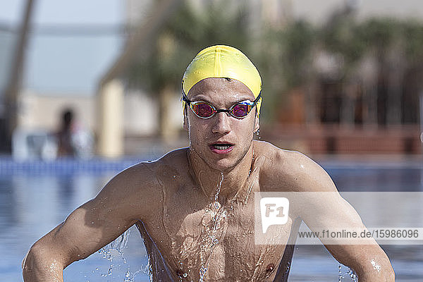 Determined male swimmer coming out from pool at tourist resort  Dubai  United Arab Emirates