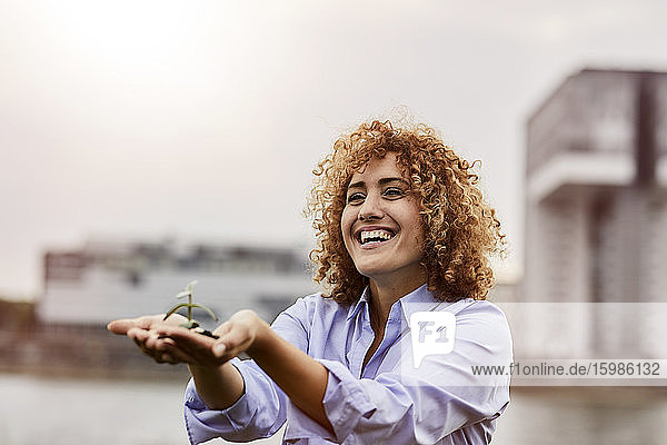 Lächelnde Frau hält Pflanze in den Händen
